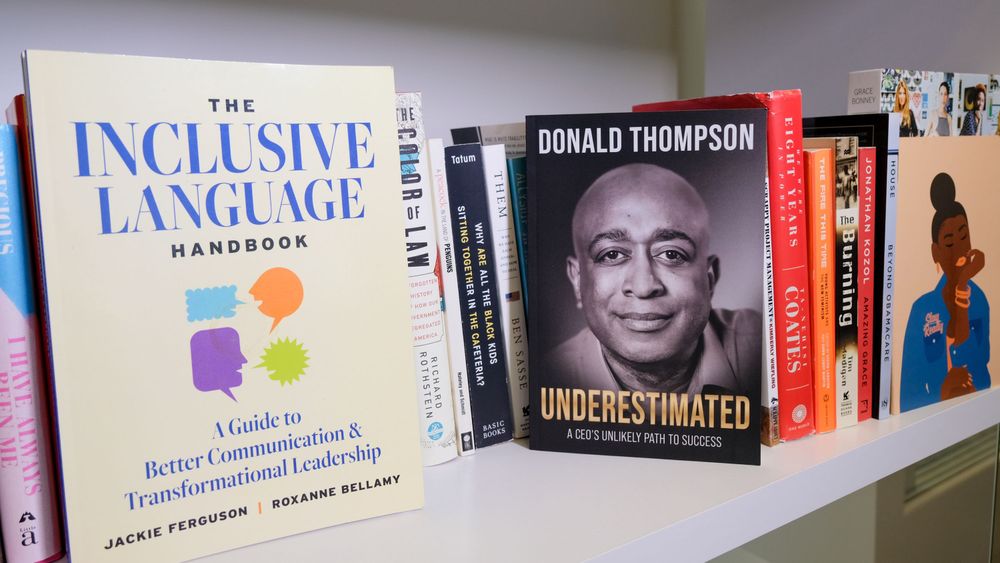 Photo of a bookshelf featuring "The Inclusive Language Handbook" and "Underestimated: A CEO's Unlikely Path to Success"