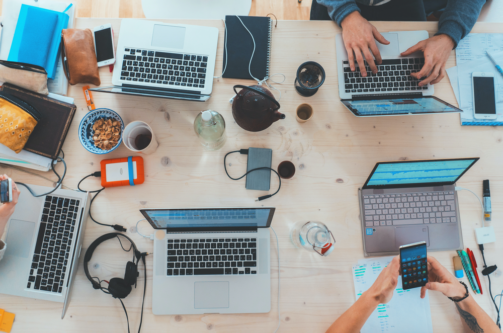 People working at table on laptops and mobile devices