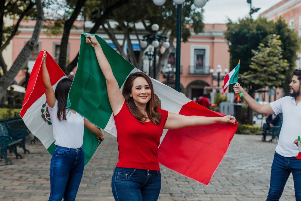 Woman wearing a red shirt holding a Mexican flag