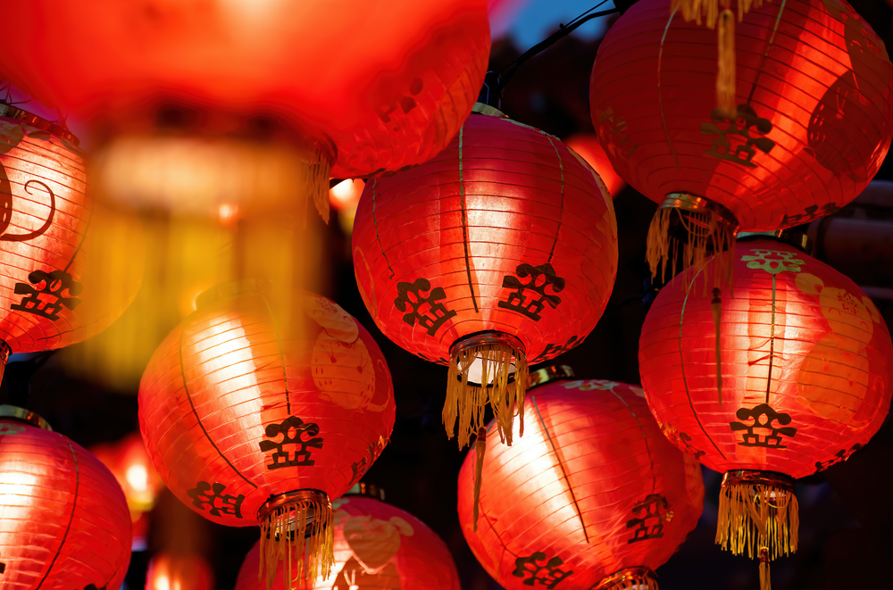 Rows of colorful glowing red Chinese lanterns hanging high across the street during Lunar New Year Celebrations.