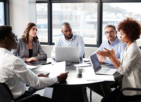 Group of diverse coworkers sitting together and collaborating at a round table.