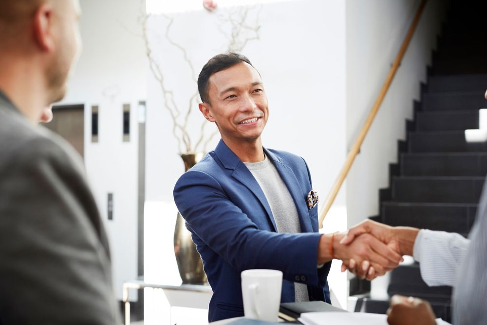 Smiling entrepreneur shaking hands with businesswoman in office