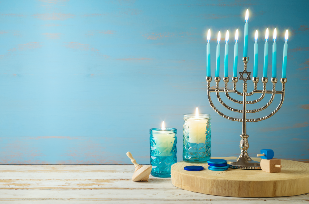 Jewish holiday Hanukkah concept with menorah, candles and dreidel on wooden table.