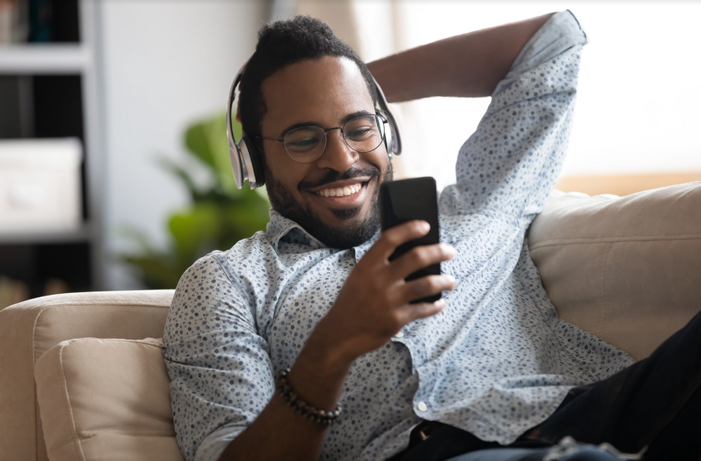Black man smiling while watching video on phone