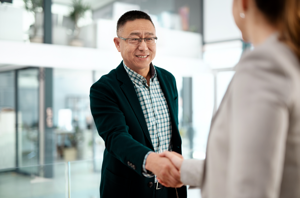 Shot of an older businessman and businesswoman shaking hands in a modern office