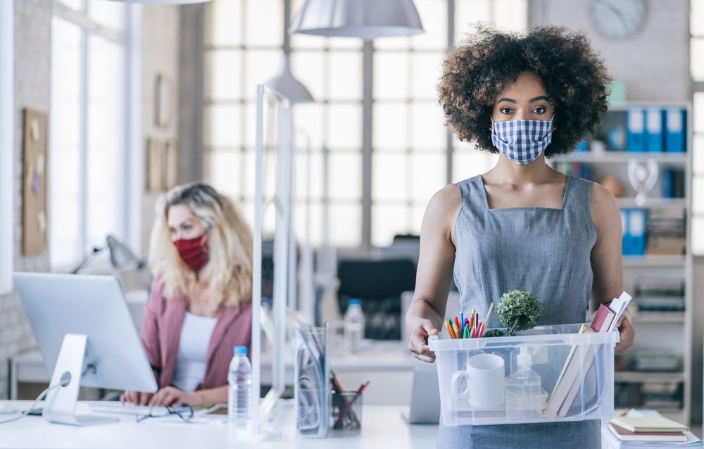 Businesswoman with protective face mask quits job due to limiting workplaces in office, during Covid-19