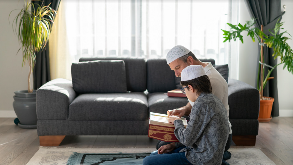 Son and father reading Quran together at home stock photo