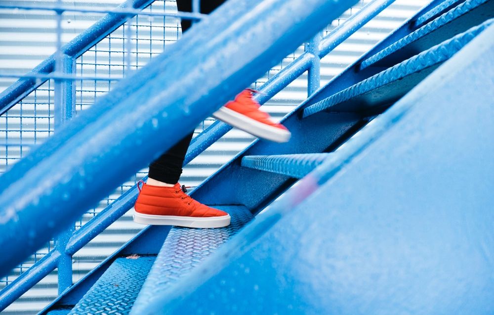 Person with red shoes walking up blue stairs