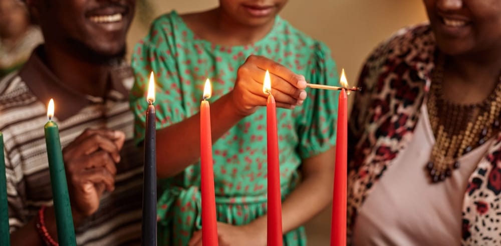 A Black family celebrates Kwanzaa by lighting the seven candles.