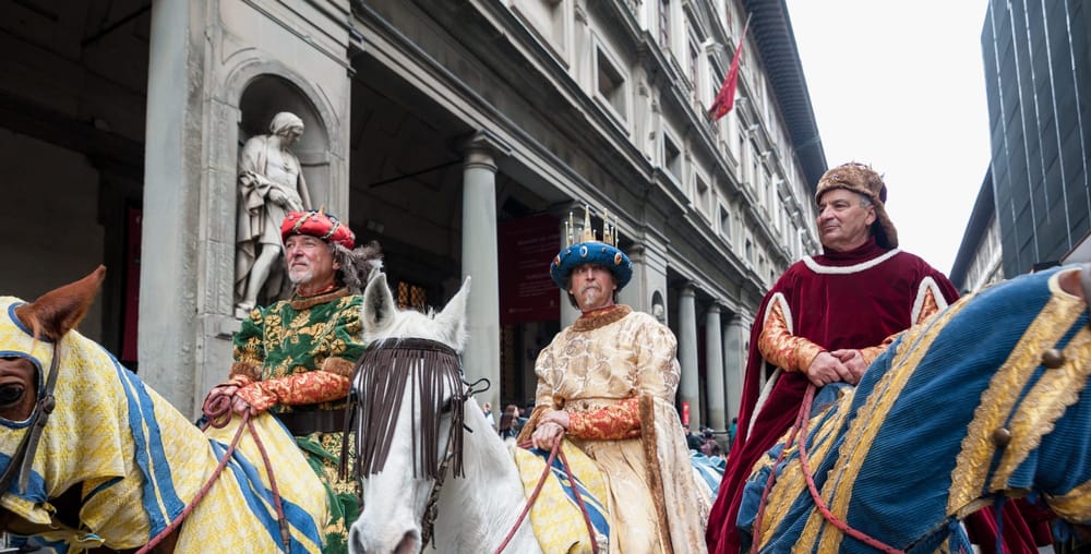 Three men in traditional clothing for Three Kinds Day ride horses in a parade in Italy