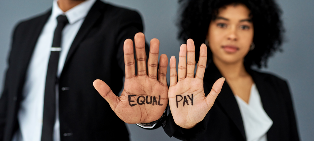 A man in a business suit with the word "Equal" and a woman in a business suit with the word "Pay"