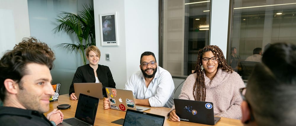 Five people sitting at an office table, three of whom are facing the camera