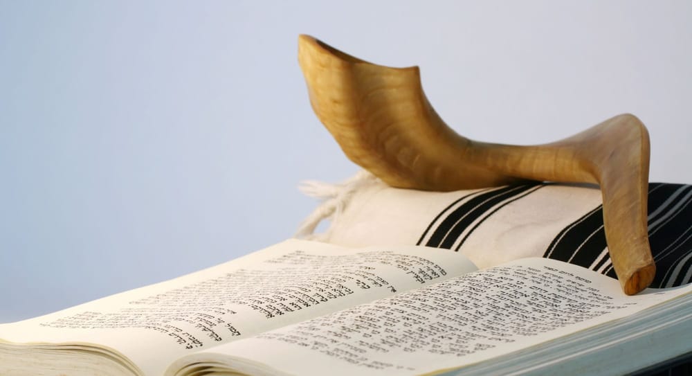 Religious Judaic objects used for prayer - a shofar, tallis, and prayer book.