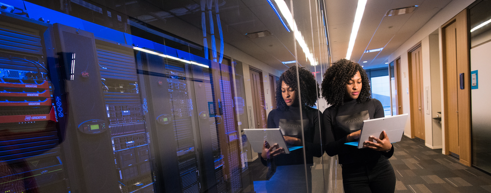 Woman coding with room of servers in background