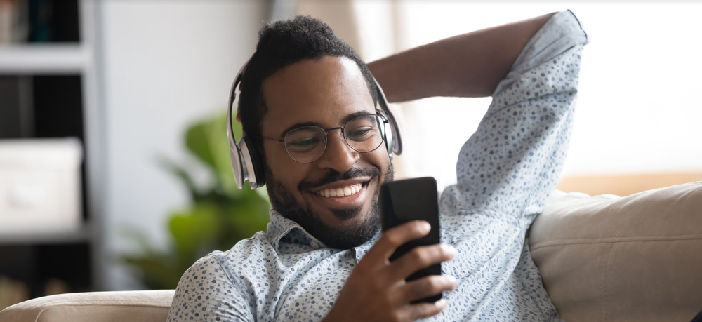 Black man smiling while watching video on phone