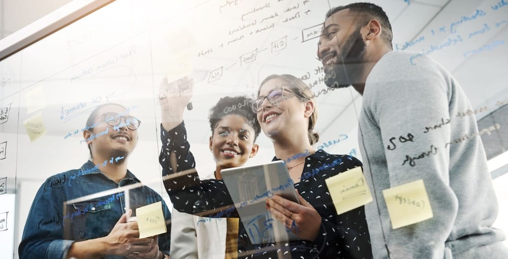 Team of four people collaborating at a whiteboard