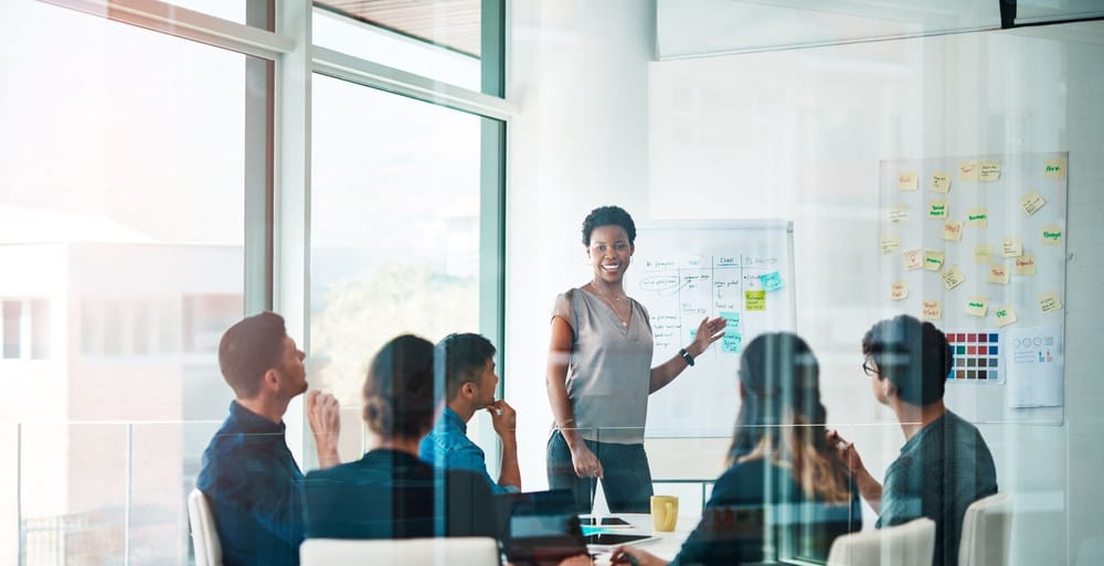 Woman with dark skin and short black hair leading a team meeting