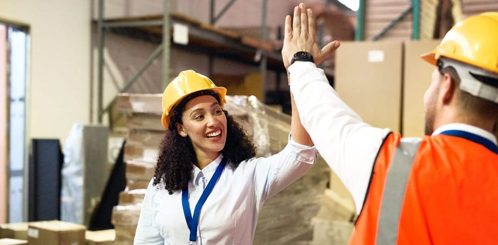 Stock photo of a woman and a man high fiving on a construction site