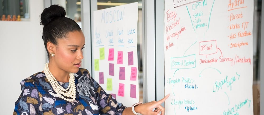 Woman of color pointing at a flipchart paper on a window