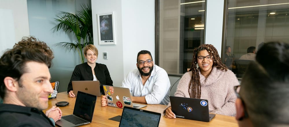 Diverse group of coworkers at conference table with laptops