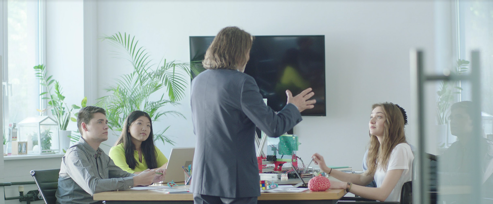 White man talking to conference room full of diverse people