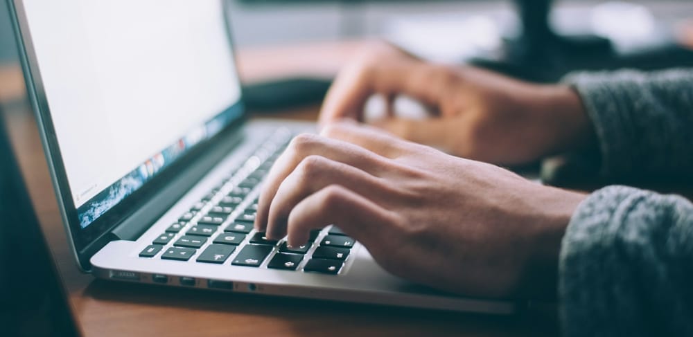 Hands type on a laptop